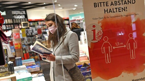 Eine Frau steht in einer Buchhandlung und betrachtet Bücher © picture alliance / SvenSimon | Frank Hoermann Foto: Frank Hoermann