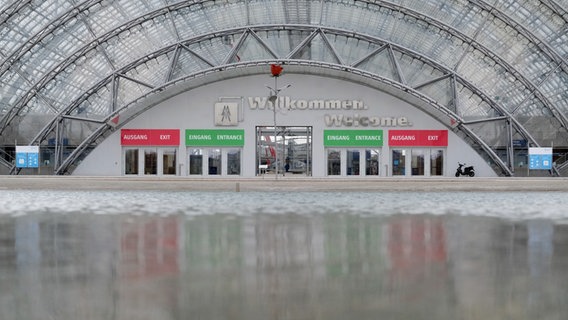 Die Fassade der Glashalle des Messegeländes der Leipziger Buchmesse spiegelt sich in einem Teich. © picture alliance/dpa/dpa-Zentralbild | Sebastian Willnow 