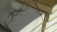 Lesebrille liegt auf einem Bücherstapel © IMAGO / CHROMORANGE 