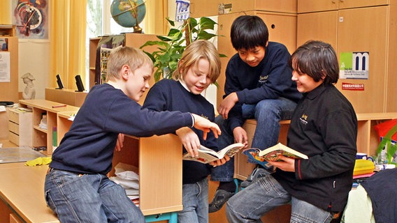 Vier Jungs blättern in einem Klassenraum in Comics. © picture alliance / dpa Foto: Jan Woitas