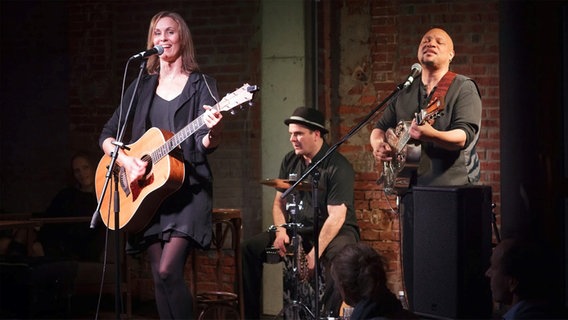Eva Kretic mit Gitarre und zwei Männern auf der Bühne. © Stefan Albrecht 