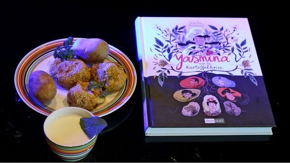 Kartoffelbällchen und Kartoffeln neben dem Buch von Wauter mannaert: "Yasmina und die Kartoffelkrise" aus eat.READ.sleep Folge 38 © NDR Foto: Tim Piotraschke
