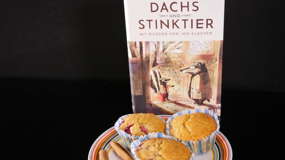 Erdbeermuffins neben einem Buch "Dachs und Stinktier"- Folge 52 von eat.READ.sleep © NDR Foto: Martin Trautvetter