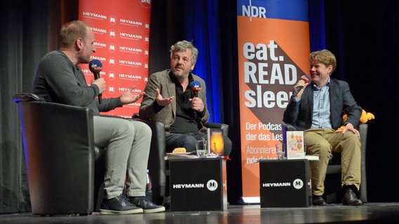 Die Hosts von eat.READ.sleep Daniel Kaiser (links), Jan Ehlert (rechts) mit Schriftsteller Matthijs Deen in Buchholz auf der Bühne der "Empore" © NDR Foto: Patricia Batlle