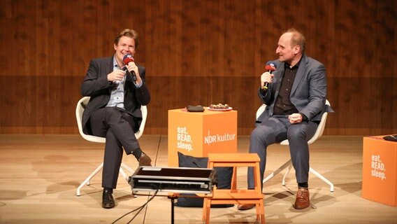 Der Bücherpodcast eat.READ.sleep. im kleinen Saal der Elbphilharmonie: Zwei Männer sitzen auf der Bühne und sprechen in Mirkophone. © NDR Foto: Sebastian Fuchs