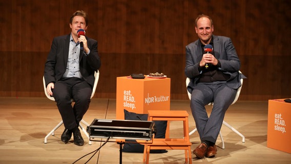 Podcasthosts Jan Ehlert (links) und Daniel Kaiser (r.) bei einer Veranstaltung des Bücherpodcasts eat.READ.sleep in 2024 © NDR Foto: Sebastian Fuchs