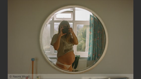 Eine schwangere Frau fotografiert sich im Spiegel; Bild von Naomi Wood aus: "Eye Mama", teNeues Verlag © Naomi Wood 