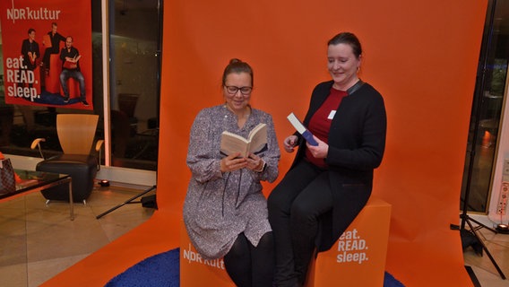Zwei Frauen lesen Bücher in einem Fotobereich zum Fanfest von eat.READ.sleep in Hannover © NDR Foto: Patricia Batlle