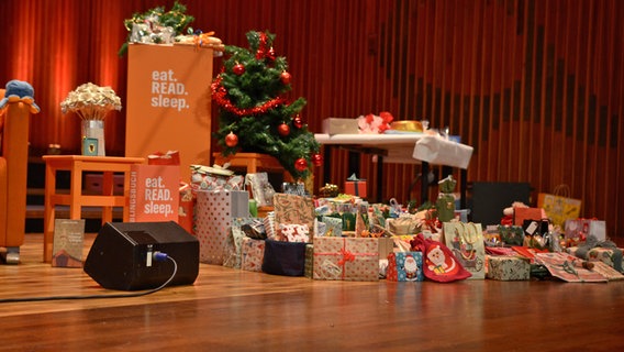 Weihnachtlich verpackte Geschenke unter einem Tannenbaum beim Fanfest zur 100. Folge von eat.READ.sleep in Hannover © NDR Foto: Patricia Batlle