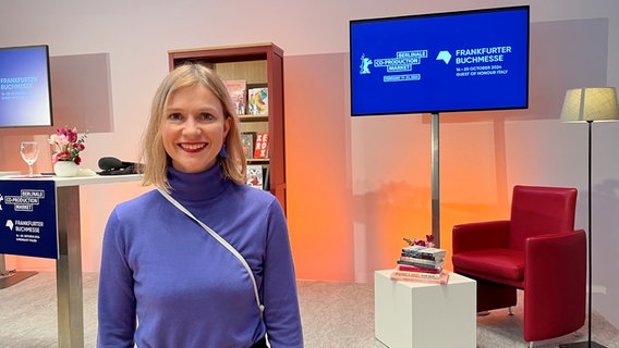 Eine Frau mit kinnlangen Haaren und blauen Pulli steht lächelnd vor einer Bühne der Berlinale (Autorin Claudia Scharf bei "Books at Berlinale") © NDR Foto: Patricia Batlle