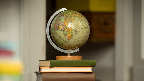 Ein Globus steht auf einem Stapel Bücher © picture alliance Foto:  complize/Shotshop