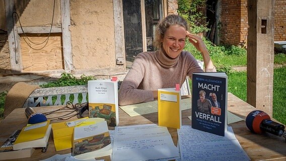 Blick auf verschiedene Bücher auf einem Tisch, dahinter Lisa Kreißler © NDR 