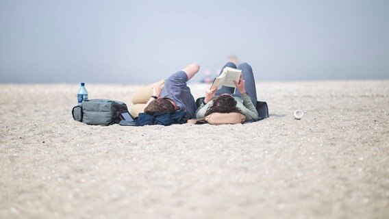 Ein Pärchen liegt lesend am Strand. © xKirchner-Media/Wedelx Foto: Kirchner-Media/Wedel Schillig