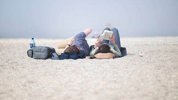 Ein Paar liest am Strand © IMAGO / Kirchner-Media 