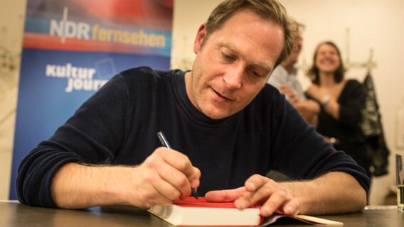 Thees Uhlmann signiert ein Buch.  Foto: Stefan Albrecht