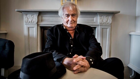 Der schwedische Schriftsteller Henning Mankell sitzt mit verschränkten Händen vor seinem schwarzen Hut vor einem Kamin(Archivbild - er starb im Oktober 2015) © picture alliance / dpa | Nora Lorek Foto: Nora Lorek