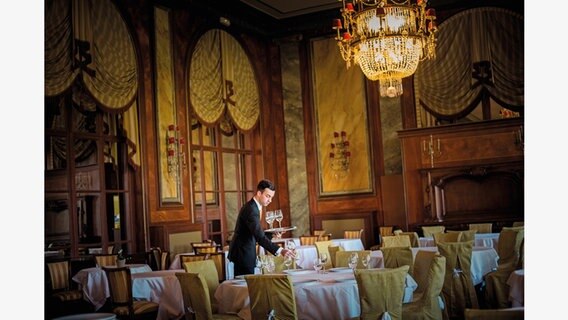 Ein Kellner deckt die Tische im Sternerestaurant. © Nicole Strasser / mare Verlag Foto: Nicole Strasser