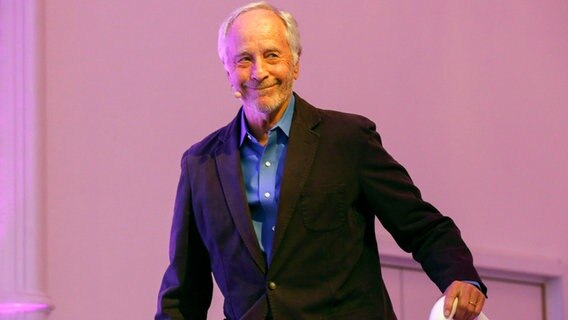 US-Autor Richard Ford lächelt im schwarzen Jackett mit blauem Hemd bei einer Veranstaltung in Deutschland © picture alliance / Geisler-Fotopress | Robert Schmiegelt/Geisler-Fotopr Foto: Robert Schmiegelt