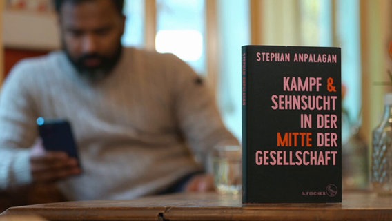 Stephan Anpalagans Buch "Kampf & Sehnsucht in der Mitte der Gesellschaft" steht auf einem Tisch © Screenshot NDR 