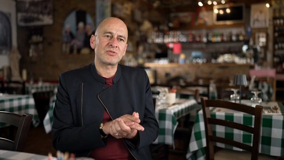 Ein Mann sitzt in einem italienischen Restaurant. © NDR Screenshot 