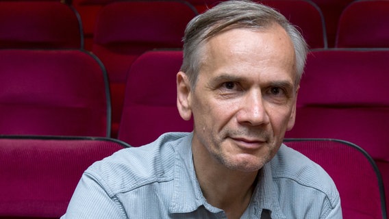 Lutz Seiler sitzt in einem Theatersaal zwischen roten Stühlen © picture alliance/dpa/dpa-Zentralbild | Hendrik Schmidt Foto: Hendrik Schmidt