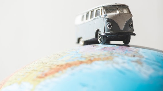 Spielzeug-VW-Bulli auf einem Globus. © colourbox Foto: Deyan Georgiev