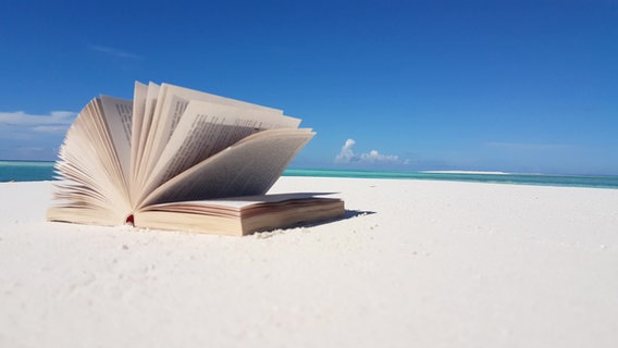 Ein aufgeschlagenes Buch liegt am Strand. © colourbox Foto: MotionWorksFilmStudio