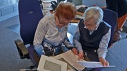 Marlen Klotz (links) und Renate Ehmke beugen sich über Schriftstücke in Sütterlin im Studio von NDR Kultur © NDR Foto: Patricia Batlle