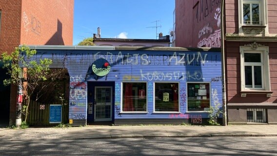 Zu sehen ist ein blaues kleines Haus, inmitten von zwei Mehrparteienhäusern in Hamburg. Zu sehen ist ein blaues kleines Haus, inmitten von zwei Mehrparteienhäusern in Hamburg. © Antonia Reiff / NDR Foto: Antonia Reiff