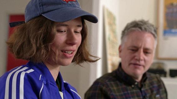 Die Comic-Zeichnerin Helena Baumeister mit blauem Käppi und Martin Vandreier sitzen in einem Raum und unterhalten sich. Die Comic-Zeichnerin Helena Baumeister mit blauem Käppi und Martin Vandreier sitzen in einem Raum und unterhalten sich. © NDR
