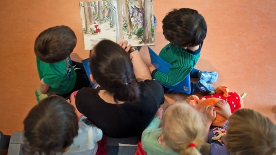 Eine Erzieherin liest Kindern aus einem Buch vor © dpa - Bildfunk / Arno Burgi 