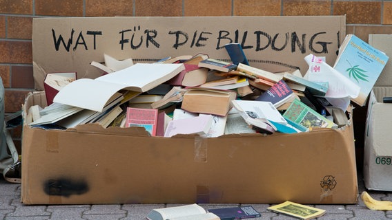 Eine Kiste zerfledderter Bücher steht am Straßenrand. © picture alliance / dpa | Boris Roessler 