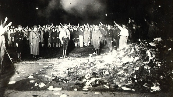 Menschen stehen um einen brennenden Haufen Bücher herum © imago 