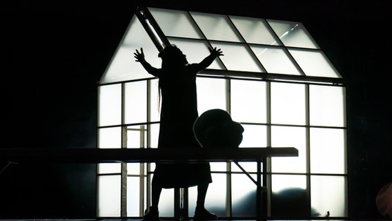 Eine Frau steht im Stück "Brüste und Eier" am Thalia Theater im Gegenlicht vor einem Gewächshaus © Krafft Angerer / Thalia Theater Foto: Krafft Angerer