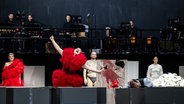 Eine Person in rotem Kostüm singt auf einer Bühne © Staatsoper Hannover / Sandra Then Foto: Sandra Then