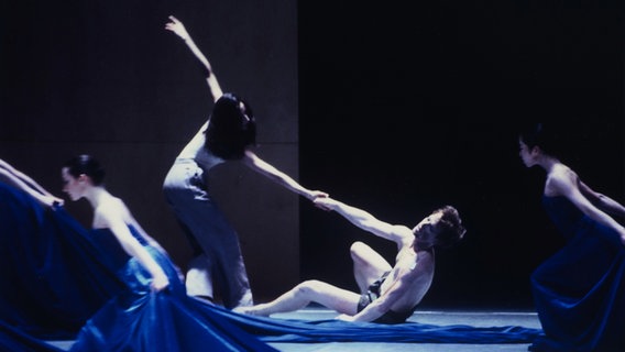 Vier Balletttänzer:innen mit blauen Schleppen auf einer Bühne © Hamburg Ballett / Holger Badekow Foto: Holger Badekow