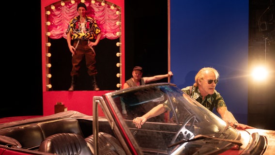 Wolfram Koch schiebt in der Rolle des Parteichefs Hoederer ein rotes Cabrio, amerikanisches Modell, im Theaterstück "Schmutzige Hände" von Jean-Paul Sartre in der Inszenierung von Jan Bosse. © Schauspielhaus Zürich Foto: Armin Smailovic