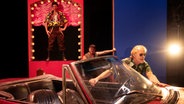Wolfram Koch schiebt in der Rolle des Parteichefs Hoederer ein rotes Cabrio, amerikanisches Modell, im Theaterstück "Schmutzige Hände" von Jean-Paul Sartre in der Inszenierung von Jan Bosse. © Schauspielhaus Zürich Foto: Armin Smailovic