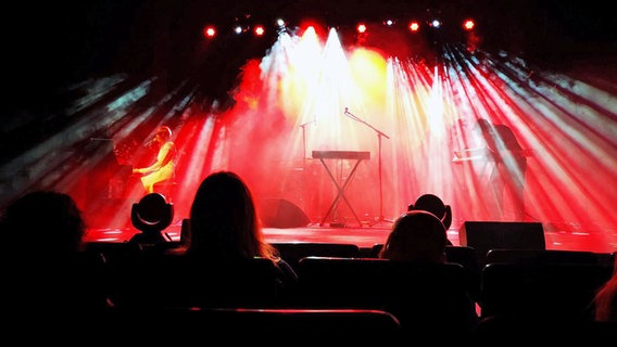 Auf einer Bühne, die in rotes Licht getaucht ist, spielen Musiker. © NDR Foto: Nora Reinhardt