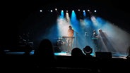 Auf einer Bühne, die in blaues Licht getaucht ist, spielen Musiker. © NDR Foto: Nora Reinhardt