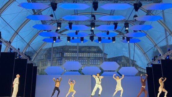 Zur Eröffnung der letzten Saison von Ballettintendant John Neumeier (l) steht er selber beim Open-Air auf dem Rathausmarkt in Hamburg mit Tänzern auf der Bühne. © dpa Foto: Carola Große-Wilde