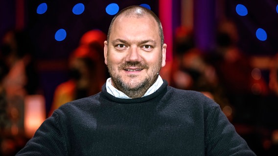 Schauspieler Charly Hübner mit einem dunklen Pullover und weißem Hemd in einer Fernsehshow im November 2022 © Imago / Star Media 