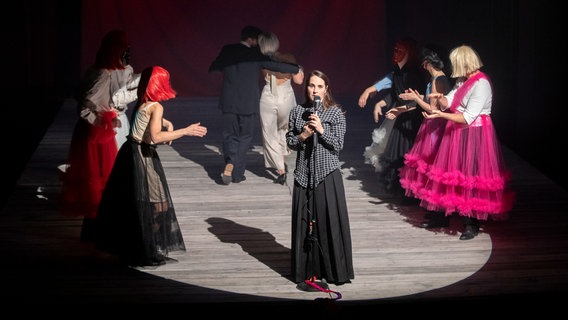 Jennifer Sabel steht in einer Szene aus "Das achte Leben" in einem Kreis aus Menschen © Silke Winkler/Mecklenburgisches Staatstheater Foto: Silke Winkler