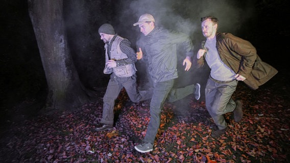 Drei Männer laufen bei Nebel durch einen Wald. Auf dem Boden liegen viele Blätter. © Olaf Struck Foto: Olaf Struck