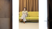 Eine Frau sitzt auf einem gelben Sofa und schaut streng. © Silke Winkler Foto: Silke Winkler