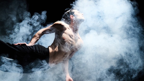 Ein Tänzer fliegt in einem Sprung über die Bühne. Er ist von Neben umgeben. © Oliver Farys Foto: Oliver Farys