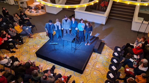 Sechs Personen stehen auf einer kleinen viereckigen schwarzen Bühne. Der Blick ist von oben nach unten. © Agnes Bührig / NDR Foto: Agnes Bührig / NDR