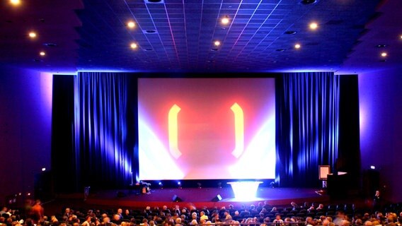 View of a crowded cinema hall with a screen and open curtains © imago / Karo 