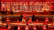Darsteller sitzt auf Bühnenrand bei dem Musical Moulin Rouge © picture alliance / Photoshot 