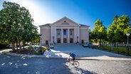 Ein Radfahrer fährt bei Sonnenschein am Landestheater Neustrelitz vorbei. © picture alliance/dpa/dpa-Zentralbild Foto: Jens Büttner